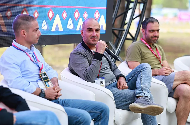 Rem Darbinyan speaking into a microphone on an outdoor festival panel